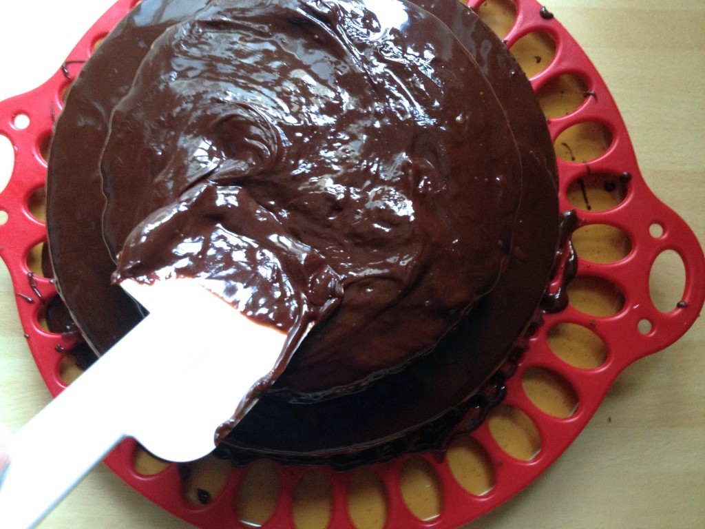 Applying chocolate glaze on the cake